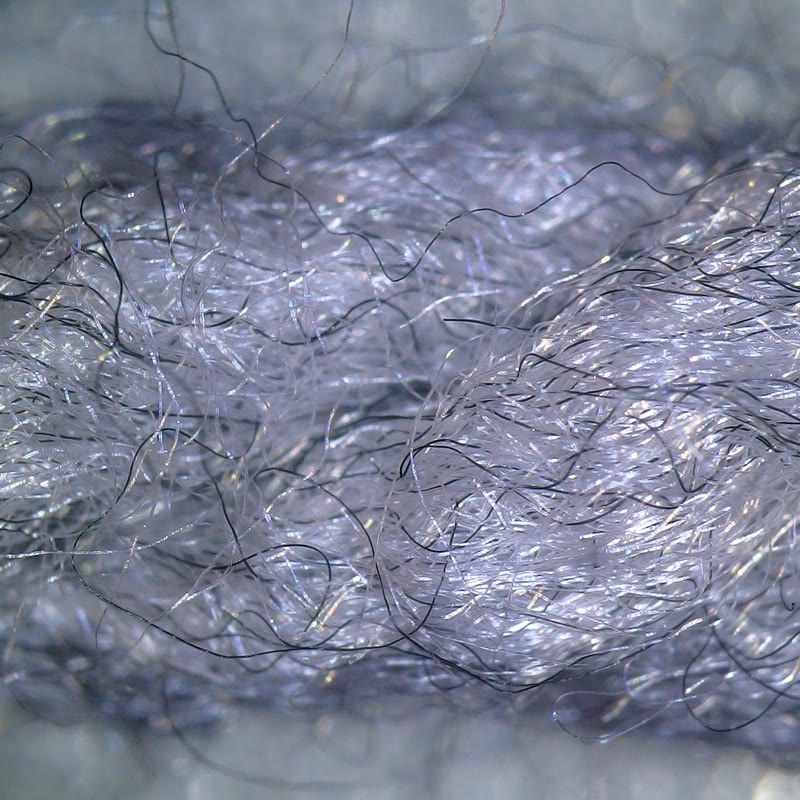 Fine acrylic yarn fibers viewed with oblique illumination in an optical microscope.