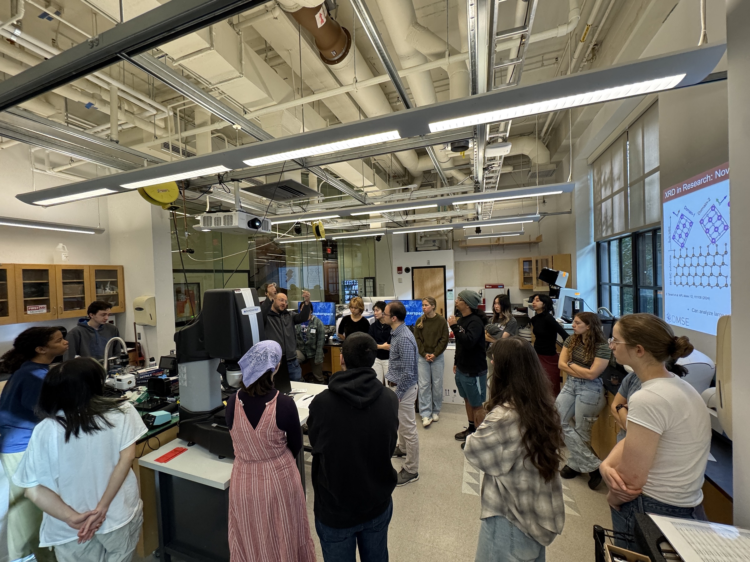 Undergraduate students gathered around the Breakerspace X-ray diffractometer during a projected lesson and instrument exercise.